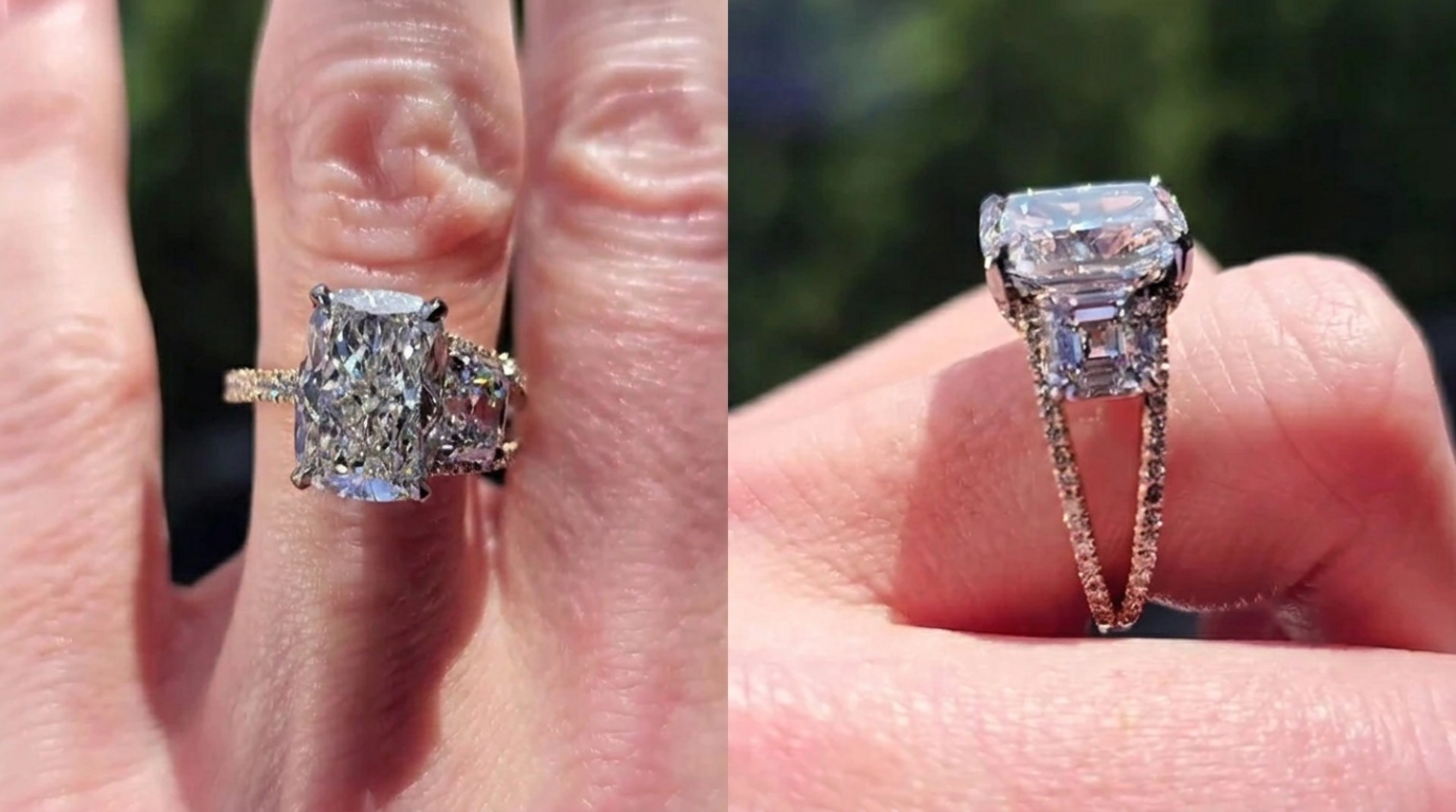 Close-up of a radiant cut three-stone diamond engagement ring featuring a large center diamond, trapezoid side stones, and a delicate pavé diamond band.